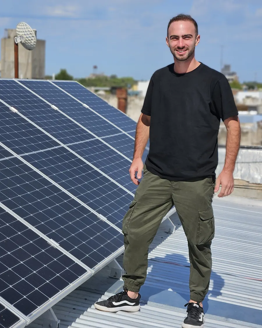 Nicolás D'Agostino, fundador de Green Renovable, sobre un techo junto a una instalación de paneles solares